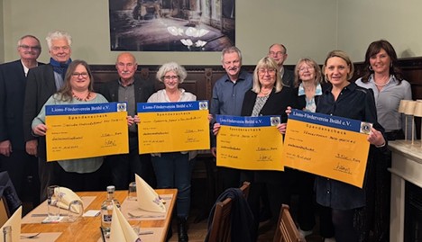 Mehrere Personen stehen zusammen. Einige halten Spendenschecks in den Händen.