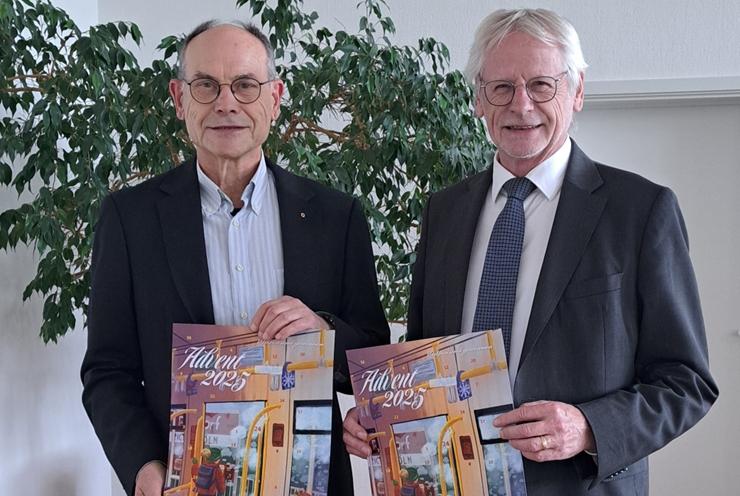 Zwei Männer stehen nebeneinander und halten den Adventskalender 2025 des Lions Club Brühl in ihren Händen